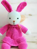 ai genererad stickat kanin i rosa klänning. st. hjärtans dag dekor. stickat leksak, amigurumi. valentines dag hälsning kort ai genererad foto