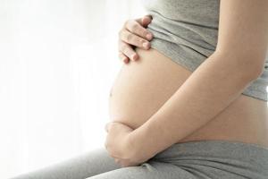 gravid kvinna som rör hennes mage på den vita bakgrunden. graviditet hälsosam moderskap koncept