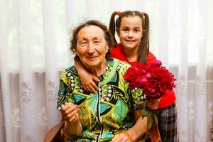 liten flicka ger henne bra mormor en rosa blomma foto