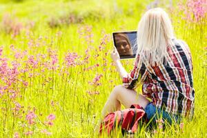 kvinna arbetssätt på läsplatta uppkopplad i sommar parkera på gräs. kvinna person företag natur utanför med uppkopplad teknologi. elektronisk gadgetar distans inlärning begrepp. foto