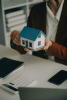 fastighetsmäklare presenterar och rådgör med kund till beslutsfattande teckna försäkringsformulär avtal, köp och sälj bostadsmodell, gällande bolåneerbjudande för och villaförsäkring foto