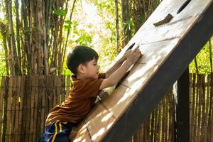 liten asiatisk pojke spelar barns sporter Utrustning utomhus foto
