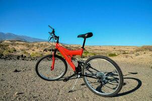 en röd berg cykel är parkerad på de öken- foto