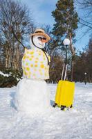 snögubbe med valise redo för resor till tropiskt land foto