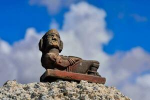 gammal mexikansk staty av en man Sammanträde på en sten foto