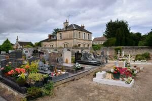 en kyrkogård med många gravar och blommor i främre av en hus foto