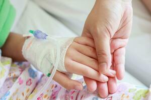 mor innehav barn hand med salin iv lösning i sjukhus foto