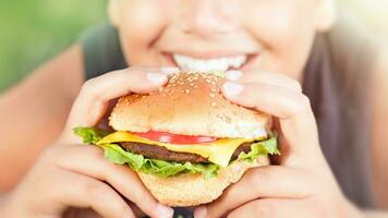 Lycklig tonåring pojke äter burger foto