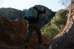 medelålders man klättrar de berg i de garraf naturlig parkera, stöds förbi vandring stolpar. foto