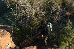 medelålders man klättrar de berg i de garraf naturlig parkera, stöds förbi vandring stolpar. foto