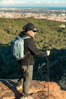 medelålders man överväger de landskap av de garraf naturlig parkera medan gående längs de spår av en berg. foto