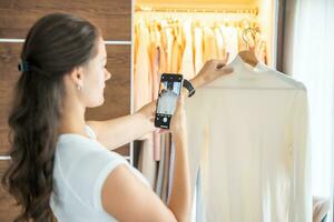 ung kvinna tar foton av gammal oönskade kläder för försäljning i smartphone app