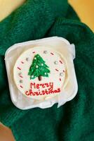 en festlig jul muffin med en grön träd och röd glad jul text på en vit glasyr. foto