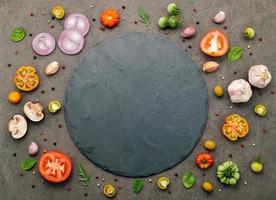 ingredienserna för hemlagad pizza uppsatt på mörk sten bakgrund. foto