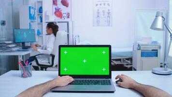 pOV skott av läkare använder sig av bärbar dator med krom nyckel i sjukhus skåp och läkare ser på röntgen bild. läkare använder sig av anteckningsbok med grön skärm på visa i medicinsk klinik. foto