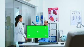 dator med grön skärm i sjukhus skåp och läkare kontroll patient röntgen. skrivbordet med utbytbar skärm i medicinsk klinik medan läkare är kontroll patient radiografi för diagnostisera. foto
