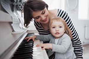 mor och dotter spelar vitt piano, närbild