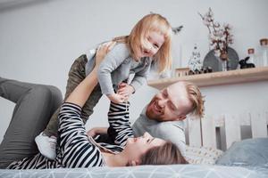 lycklig familj mamma, pappa och barn dotter skrattar i sängen foto