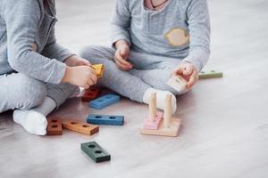 barn leker med en leksaksdesigner på golvet i barnrummet. två barn som leker med färgglada block. dagis pedagogiska spel