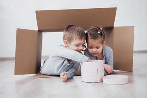 babybror och barnsyster som leker i kartonger i barnkammaren foto