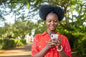 skön ung afrikansk kvinna känsla upphetsad och Lycklig, fröjd medan ser på henne telefon foto