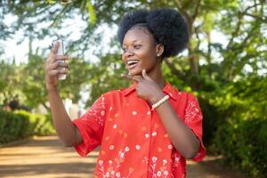 skön ung afrikansk kvinna känsla upphetsad och Lycklig, fröjd medan ser på henne telefon foto