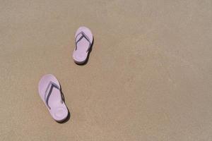 rosa strandpromenad tofflor eller sandlar av ung kvinna som placerar på vit strand och blått hav på sommarlovet. resekoncept foto