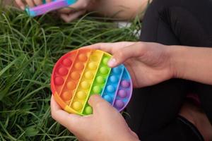 tjejer spelar färgglada silikon touch populär pop-it leksak utomhus på grönt gräs foto