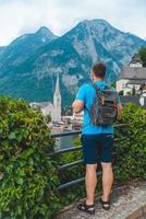 man med ryggsäck tittar på hallstatt city foto