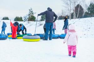 människor som åker snöslangar på vinterparken foto