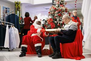 äldre man mottar närvarande från santa Nästa till jul träd, känsla Lycklig i festlig Kläder Lagra. afrikansk amerikan arbetstagare spridning positivitet förbi ger gåva till kunder. foto