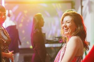 leende Lycklig caucasian kvinna skrattande medan klubba på diskotek på dansgolv i nattklubb med strålkastare. glad flicka dans och har roligt, njuter nattliv fritid i klubb foto