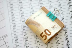 högen av euro pengar räkningar i brevpapper klämma på papper med beräkningar och kvitton. företag och bokföring begrepp foto