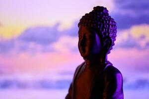 buddha purnima och Vesak dag begrepp, buddha staty med låg nyckel ljus mot skön och färgrik bakgrund. meditation foto