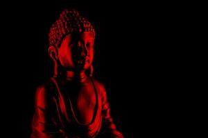 buddha purnima och Vesak dag begrepp, röd buddha staty med låg nyckel ljus mot djup svart bakgrund foto