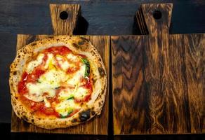 napolitansk pizza på ett mörkt träskärbräda foto