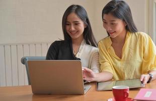 två kvinnliga studenter använder en bärbar dator för att studera online hemma för att förhindra covid-19-virusutbrottet.
