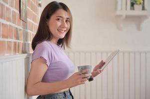 ung kvinnlig student med kaffe sittande bekvämt använde surfplatta för videosamtal med vänner hemma. foto