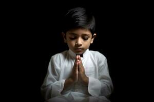 ai genererad en ung pojke bön- i en mörkare rum med hans händer tillsammans. foto