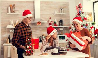 senior man och kvinna fira jul med barnbarn innehav gåva lådor. Lycklig kärleksfull farföräldrar fira vinter- högtider och relation med barnbarn i Hem med x-mas dekoration. foto