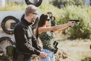 en vapen instruktör lär en flicka till skjuta en pistol på en bränning räckvidd foto