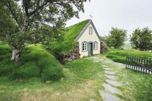 en liten träkyrka och kyrkogård hofskirkja hof, skaftafell island. naturskön solnedgång genom trädkronor foto