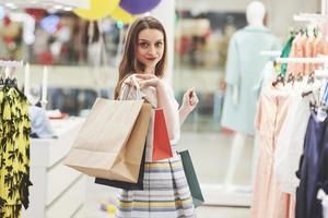 kvinna i shopping. glad kvinna med shoppingkassar som njuter i shopping. konsumentism, shopping, livsstilskoncept foto