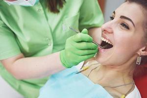 tandläkare som botar en kvinnlig patient i stomatologin. tidigt förebyggande och munhygienkoncept foto