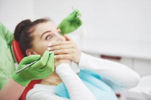 rädd flicka på tandläkarkontoret täckt med händerna. koncept fobi tandläkare foto
