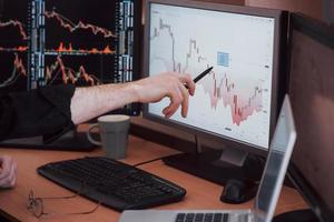 analysera data. närbild av ung affärsman som pekar på data som presenteras i diagrammet med penna medan han arbetar på kreativa kontor