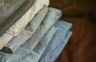 många jeans i stack i garderob rum. rad av byxor denim jeans i garderob. begrepp av köpa, sälja, handla och modern kläder foto