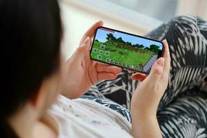 Minecraft mobil ios spel på iphone 15 smartphone skärm i kvinna händer under mobil gameplay foto