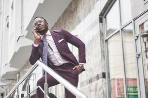 porträtt av en ung och stilig afroamerikansk affärsman som pratar i kostym över telefon. förbereder sig för ett affärsmöte.