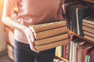 en ung tjejstudent som letar efter litteratur nära bokhyllorna i det gamla biblioteket foto